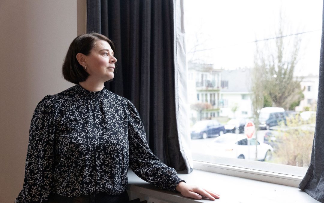 Woman looking out a window in quiet reflection — Pronoia Communications founder